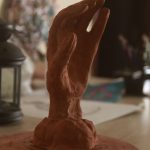 Clay sculpture of a hand in an art studio, showing craftsmanship and creativity.