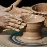 Close-up of hands shaping pottery on a wheel, showcasing artisan skills.